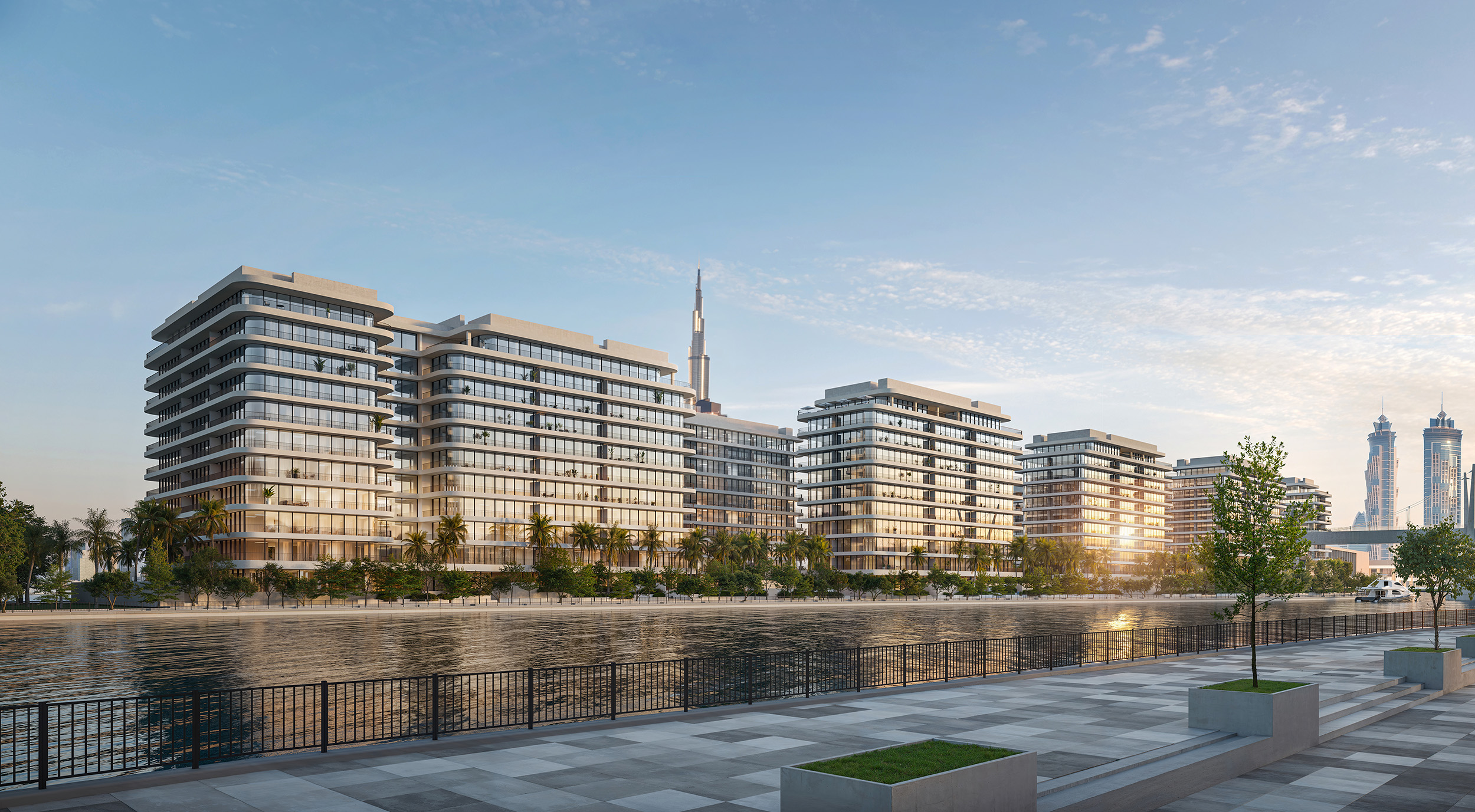 The seven low-rise buildings of Eden House The Park along the Dubai Water Canal at first light, the Downtown skyline beyond